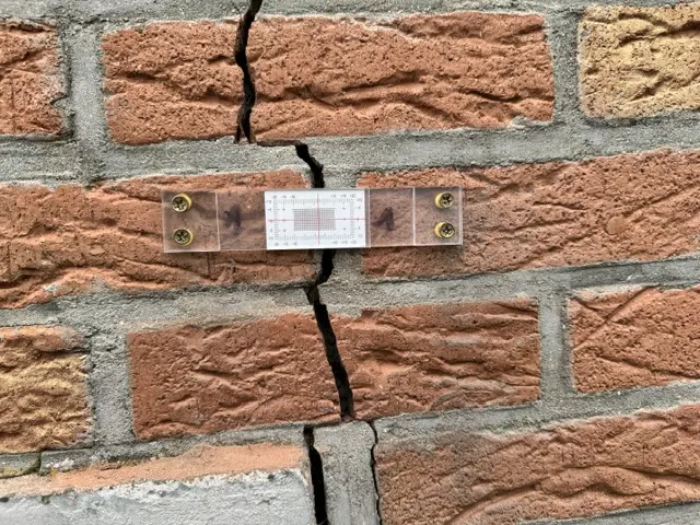 Jauge installée sur une fissure traversant une maçonnerie en briques